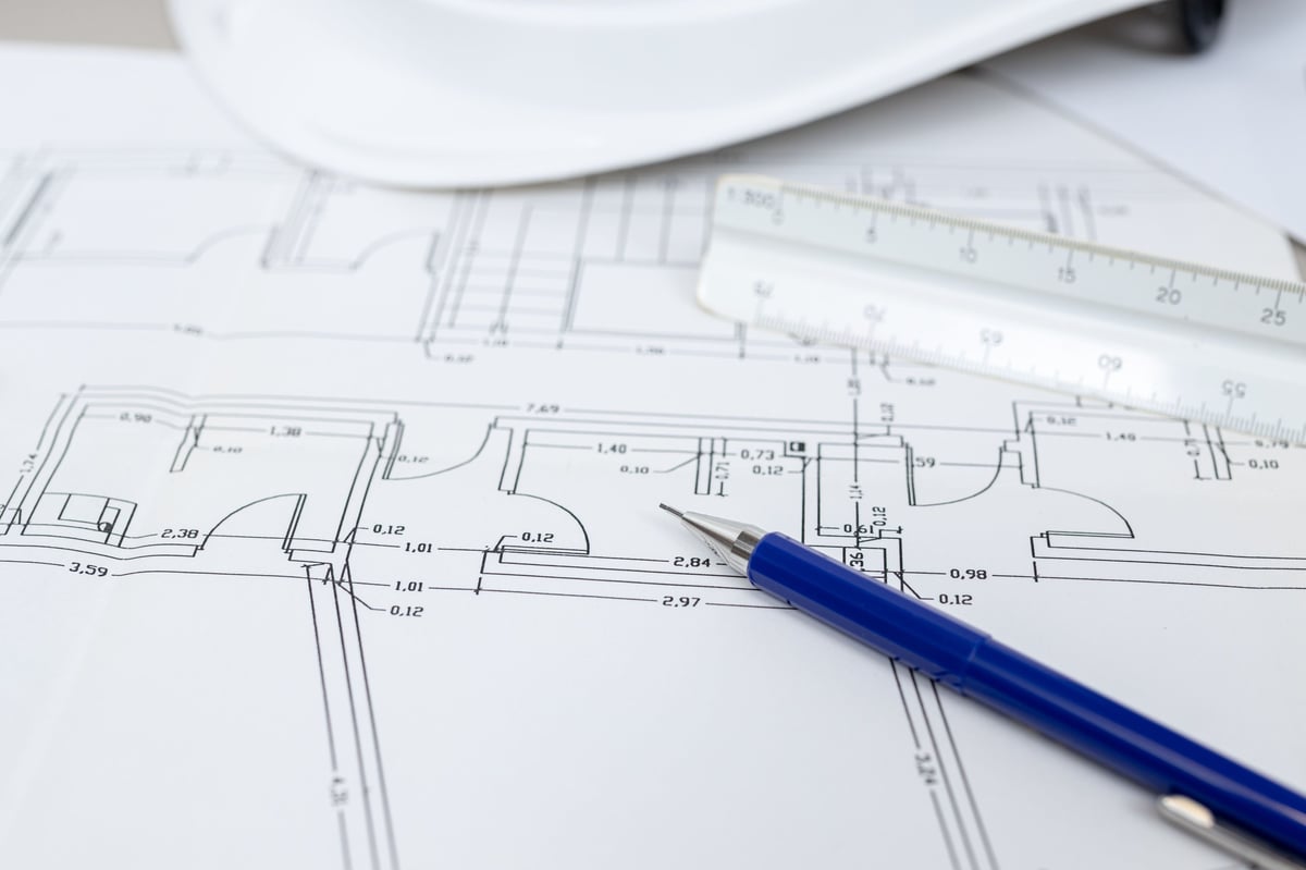 Close-up of construction blueprints with a blue pen resting on them